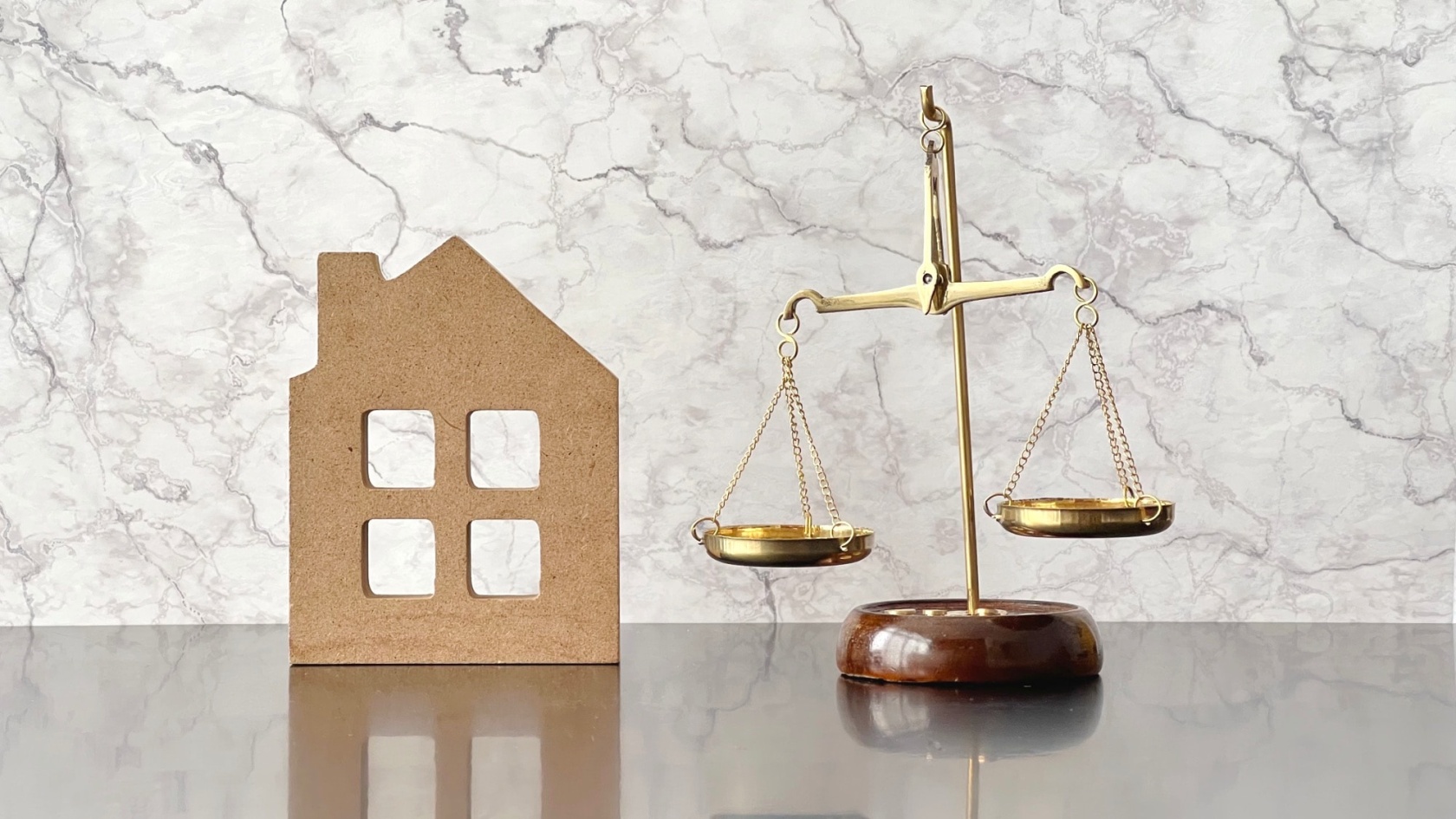 家づくりを進める上で、どちらがお得かを考えているさまを、住宅小物と天秤を用いて表現しているイメージ写真